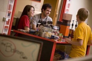 student workers at a cashier help another student at a cafe on campus